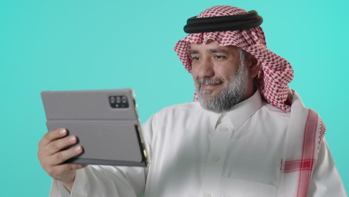 رجل سعودي يتفاعل مع جهاز لوحي رقمي في تصوير استوديو
