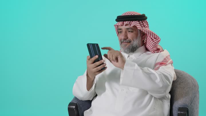 رجل سعودي يستخدم الهاتف الذكي بخلفية ملونة