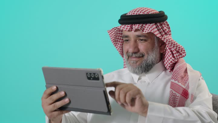 رجل سعودي يستخدم جهاز لوحي بخلفية ملونة