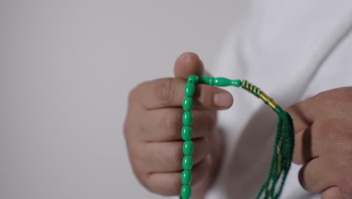 Close Up of Man Holding Green Prayer Beads