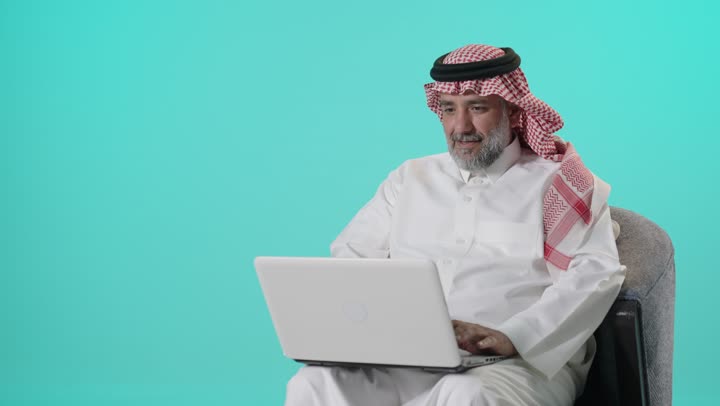 Saudi Man Using Laptop on Turquoise Background