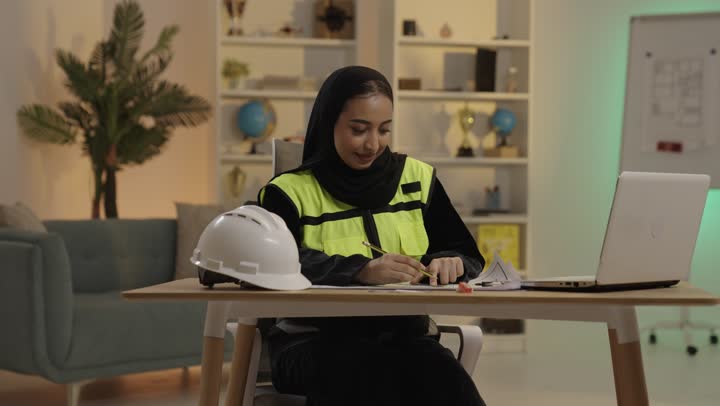 Saudi Female Engineer Working on Blueprints in Office