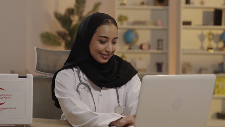 طبيبة عربية تعمل على جهاز الكمبيوتر المحمول في المكتب