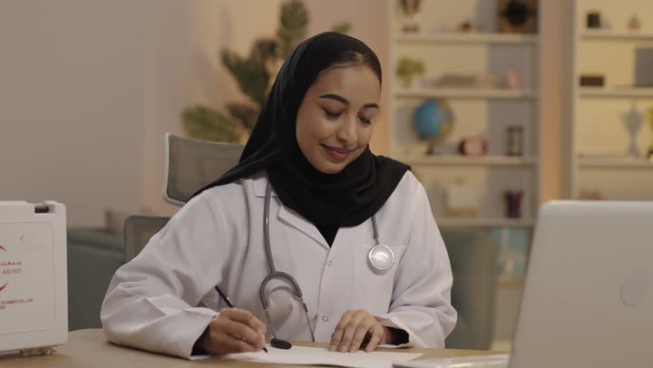 Arab Female Doctor Writing Medical Notes in Office