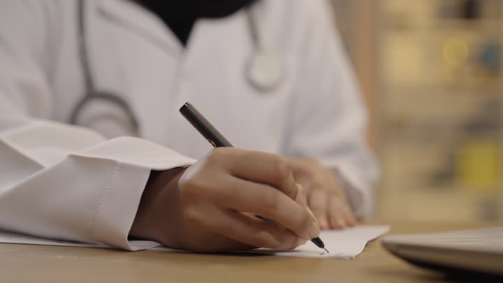 Female Saudi Doctor Writing Prescription in Clinic