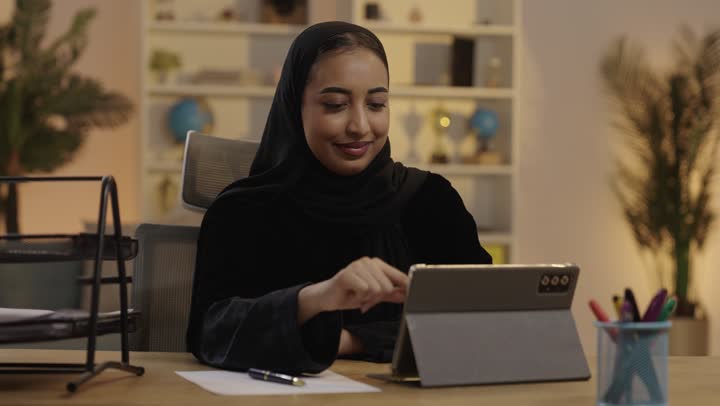 امرأة سعودية تستخدم جهاز لوحي في بيئة مكتبية