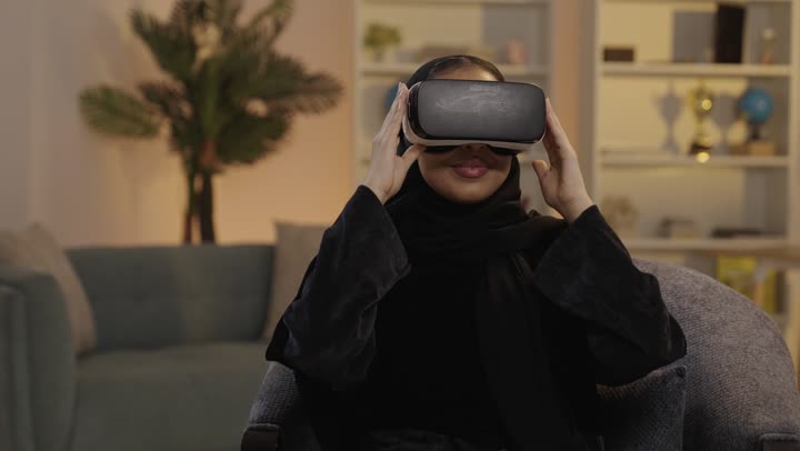 امرأة عربية تستخدم نظارات الواقع الافتراضي في المنزل