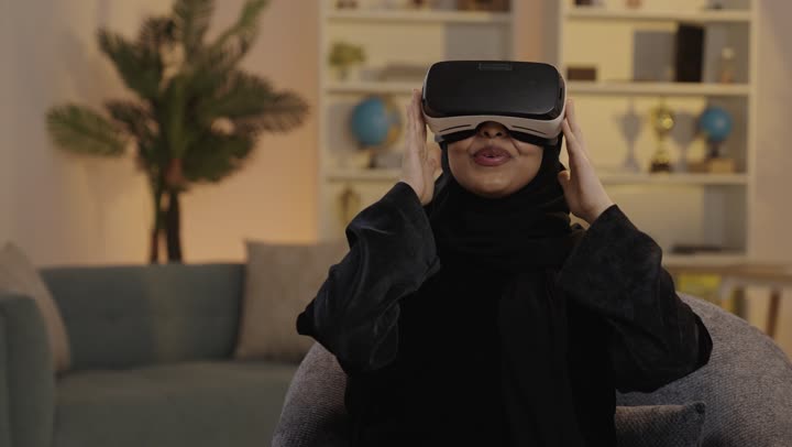 امرأة عربية تستخدم نظارة الواقع الافتراضي في المنزل