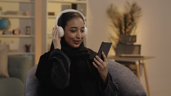 Saudi Woman with Headphones Using Smartphone at Night
