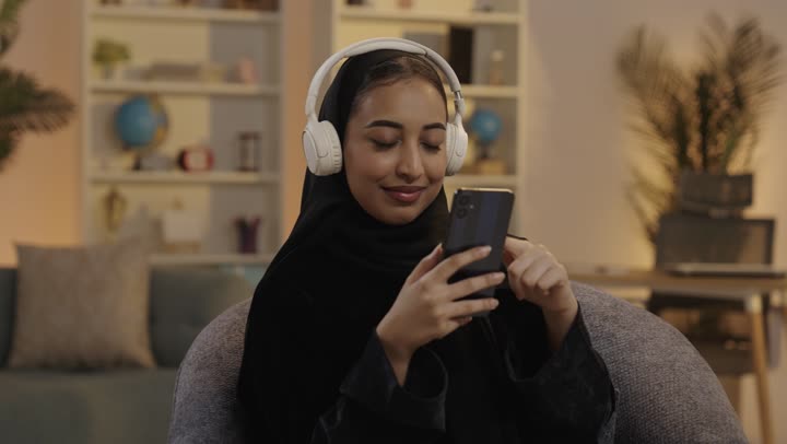Saudi Woman Using Smartphone and Headphones at Night