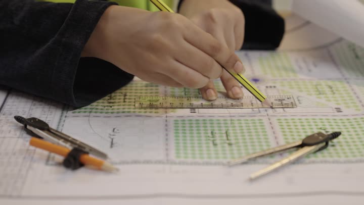 مهندسة ترسم مخطط بناء هندسي باستخدام المسطرة