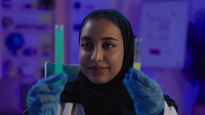 عالمة عربية في المختبر تحمل أنابيب اختبار