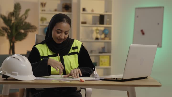Saudi Female Engineer Working on Blueprints in Office