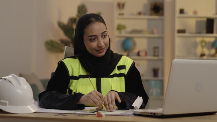 Saudi Female Engineer Working on Blueprints in Office