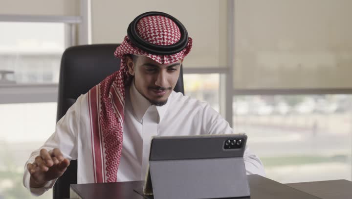 تحقيق الاستفادة القصوى من الاجهزة التقنية الحديثة , رجل عربي خليجي سعودي يرتدي الثوب الابيض و الشماغ الملون يتصفح البيانات المحفوظة على الجهاز اللوحي , استخدام الطرق الحديثة في الاعمال اليومية