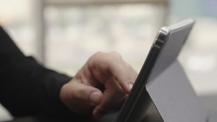 مراجعة الاعمال اليومية بسهولة من اي مكان , رجل يرتدي البذلة الرسمية السوداء ينظر الى المعلومات المسجلة على الجهاز اللوحي , تصوير مقرب