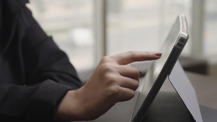 Viewing the statistics related to the company's performance using a tablet, an Arab Gulf Saudi woman wearing a black abaya touches the screen of the technical device, the optimal use of modern devices.