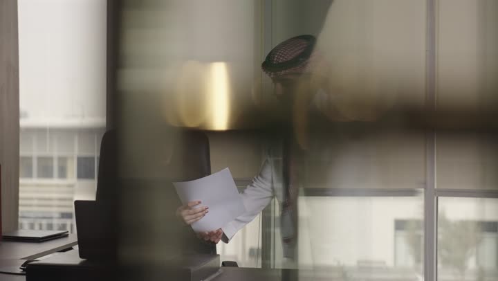 مهندس عربي خليجي سعودي يرتدي الثوب الابيض و الشماغ الملون يقوم باعطاء التوجيهات للمهندسين المبتدئين , مهندسة عربية خليجية سعودية محجبة ترتدي العباءة السوداء تستمع الى شرح المدير عن كيفية انجاز العمل