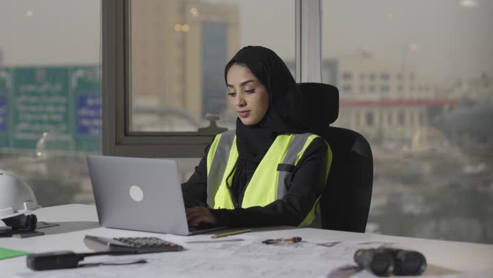 استخدام الحاسب المتنقل في مجال الهندسة و التخطيط العمراني , مهندسة عربية خليجية سعودية ترتدي عباءة سوداء تكتب التعديلات الخاصة بالمشروع الهندسي