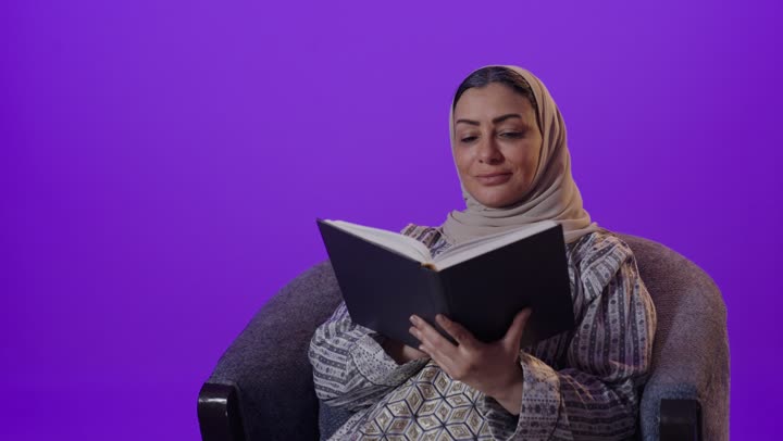 الشعور بالراحة والطمأنينة, قراءة الروايات والقصص الممتعة،  بورتريه لإمرأة كبيرة بالسن عربية خليجية سعودية محجبة ترتدي العباءة تمسك بيدها الكتاب، الاسترخاء والاستمتاع بالأجواء الهادئة، اتباع أسلوب حياة صحي، خلفية بنفسجية