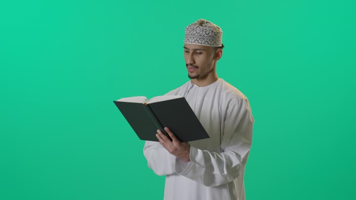 بورتريه لطالب عربي خليجي عماني يرتدي الدشداشة والكمه العمانية يمسك بيده كتاب, تنمية مهارات القراءة، قضاء أوقات الفراغ بالتثقيف والتعلم, الاهتمام بتصفح الكتب المفيدة, خلفية خضراء