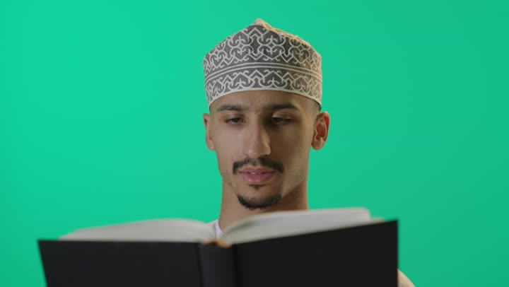 قضاء أوقات الفراغ بالتثقيف والتعلم, الاهتمام بتصفح الكتب المفيدة, بورتريه لطالب عربي خليجي عماني يرتدي الدشداشة والكمه العمانية يمسك بيده كتاب, تنمية مهارات القراءة، خلفية خضراء