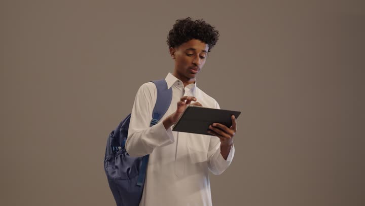 شاب سعودي بالثوب يستخدم جهاز لوحي في الاستوديو