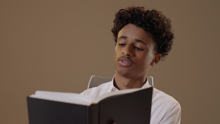 تعابير الاجتهاد والجد والنشاط, الاهتمام بتصفح الكتب المفيدة، الاستعداد للعام الدراسي الجديد، مراجعة الدروس اليومية,  بورتريه لشاب عربي خليجي سعودي اسمر يرتدي الثوب التقليدي يقوم بقراءة كتاب, خلفية بيج