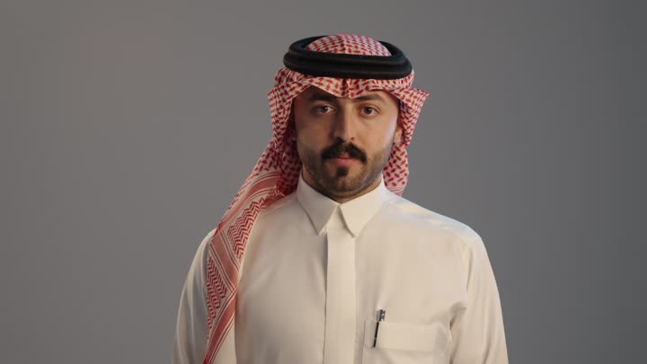 التقييم السلبي والفشل, عدم الإعجاب وعدم قبول شيء ما, بورتريه لرجل عربي خليجي سعودي يرتدي الثوب التقليدي والشماغ,  إيماءات إبهام لأسفل تدل على الرفض والإستياء وعدم الرضا, خلفية رمادية