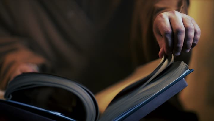 An elderly Arab Saudi Gulf man wearing a bisht and agal is reading an old historical book about Foundation Day, the anniversary of the establishment of the first Saudi state by Imam Muhammad bin Saud, which began on February 22, 1727. The pride in the nation's achievements and the realization of national identity.