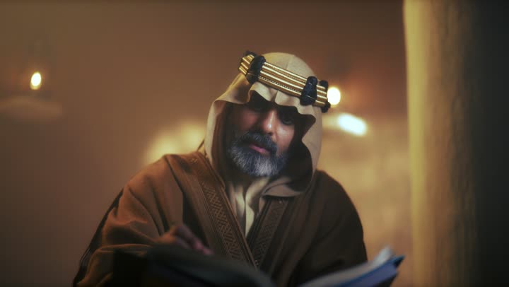 An elderly Arab Saudi Gulf man wearing a bisht and agal is reading an old historical book about Foundation Day, the anniversary of the establishment of the first Saudi state by Imam Muhammad bin Saud, which began on February 22, 1727. The pride in the nation's achievements and the realization of national identity.
