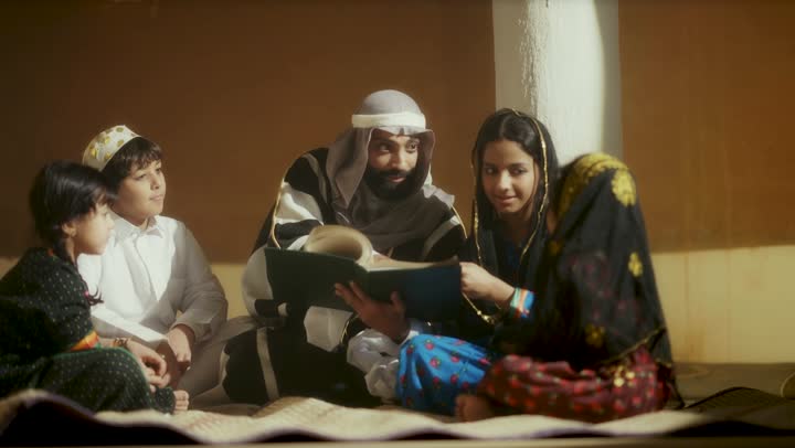 A Saudi Arabian man from the Gulf region, wearing a bisht and agal, sits with a group of children on the anniversary of the founding of the first Saudi state by Imam Muhammad bin Saud, February 22, 1727, the day we began, expressing pride in the nation's achievements and the realization of national identity.