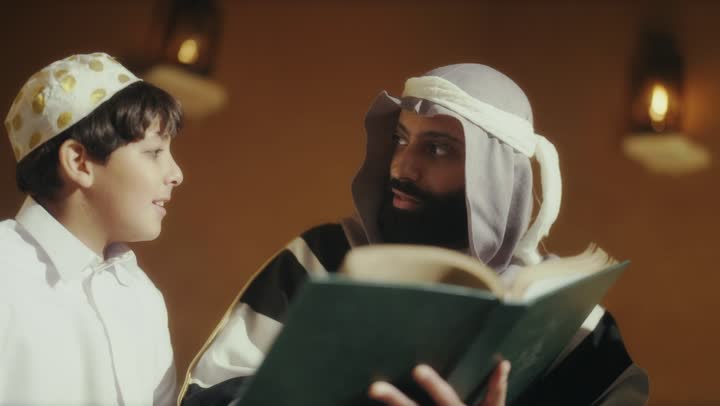 رجل عربي سعودي خليجي يرتدي البشت وعقال يوم التأسيس يجلس مع مجموعه من الاطفال ويقرأ لهم كتاب تاريخي قديم, ذكرى تأسيس الدوله السعوديه الاولى على يد  الامام محمد بن سعود, يوم بدينا 22 فبراير 1727م, الفخر بإنجازات الوطن, تحقيق الهويه الوطنيه