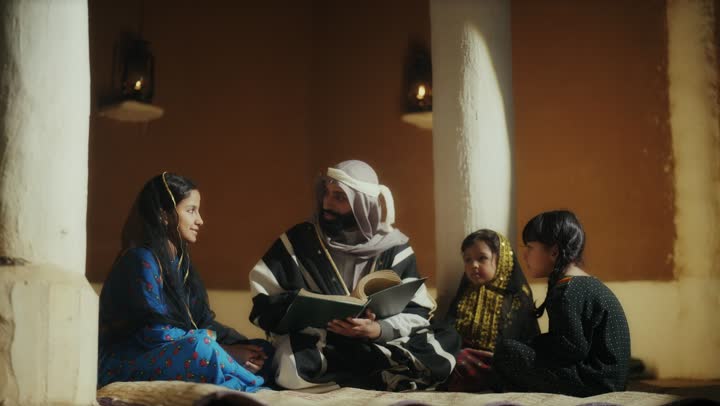 رجل عربي سعودي خليجي يرتدي البشت وعقال يوم التأسيس يجلس مع مجموعه من الاطفال ويقرأ لهم كتاب تاريخي قديم, ذكرى تأسيس الدوله السعوديه الاولى على يد  الامام محمد بن سعود, يوم بدينا 22 فبراير 1727م, الفخر بإنجازات الوطن, تحقيق الهويه الوطنيه