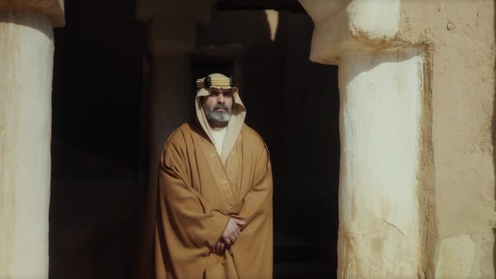 رجل  كبير السن عربي سعودي خليجي يرتدي البشت وعقال يوم التأسيس  يقف في مبنى طيني شعبي قديم بتعابير الجدية والحزم, ذكرى تأسيس الدوله السعوديه الاولى على يد  الامام محمد بن سعود, يوم بدينا 22 فبراير 1727م, الفخر بإنجازات الوطن, تحقيق الهويه الوطنيه