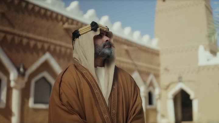 رجل  كبير السن عربي سعودي خليجي يرتدي البشت وعقال يوم التأسيس  يقف في مبنى طيني شعبي قديم النظر لشيء ما في الأعلى, ذكرى تأسيس الدوله السعوديه الاولى على يد  الامام محمد بن سعود, يوم بدينا 22 فبراير 1727م, الفخر بإنجازات الوطن, تحقيق الهويه الوطنيه