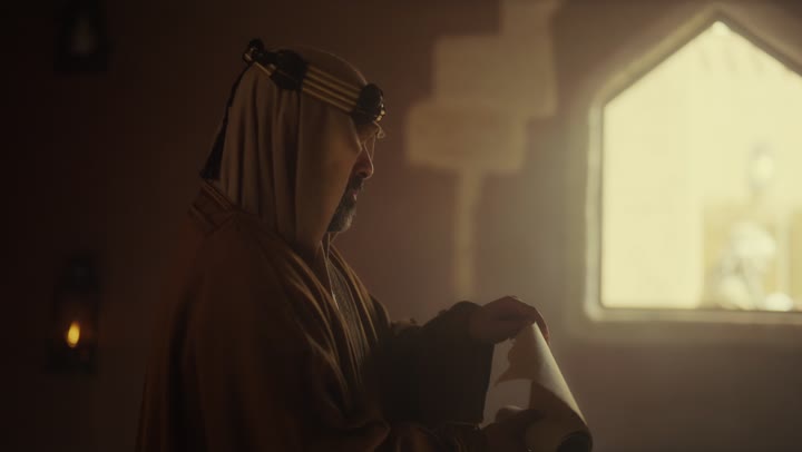 رجل  كبير السن عربي سعودي خليجي يرتدي البشت وعقال يوم التأسيس يفتح لفافه ورقيه قديمه, ذكرى تأسيس الدوله السعوديه الاولى على يد  الامام محمد بن سعود, يوم بدينا 22 فبراير 1727م, الفخر بإنجازات الوطن, تحقيق الهويه الوطنيه، خلفية نور يدخل من الشباك