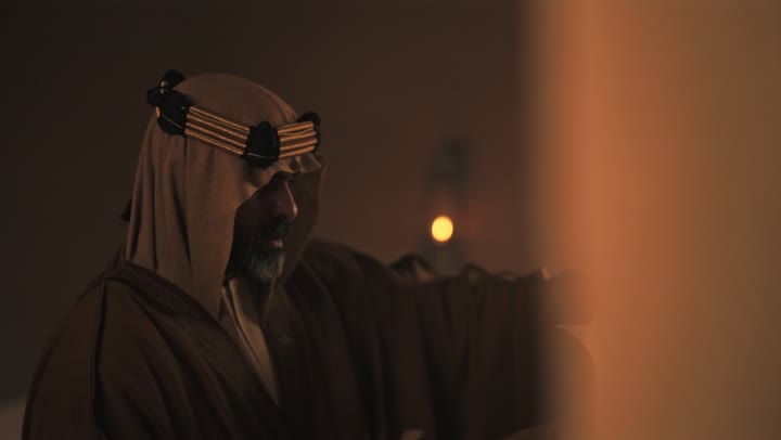 An elderly Arab Saudi Gulf man wearing a bisht and agal on Foundation Day opens an old paper wrap and reads with focused expressions, commemorating the founding of the first Saudi state by Imam Muhammad bin Saud, on the day we began, February 22, 1727 AD, pride in the nation's achievements, and the realization of national identity.