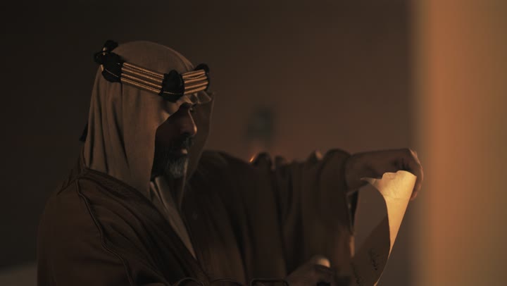 An elderly Saudi Arabian man, wearing a bisht and agal, opens an old paper roll on the anniversary of the founding of the first Saudi state by Imam Muhammad bin Saud, February 22, 1727 AD, a day of pride in the nation's achievements and the realization of national identity.