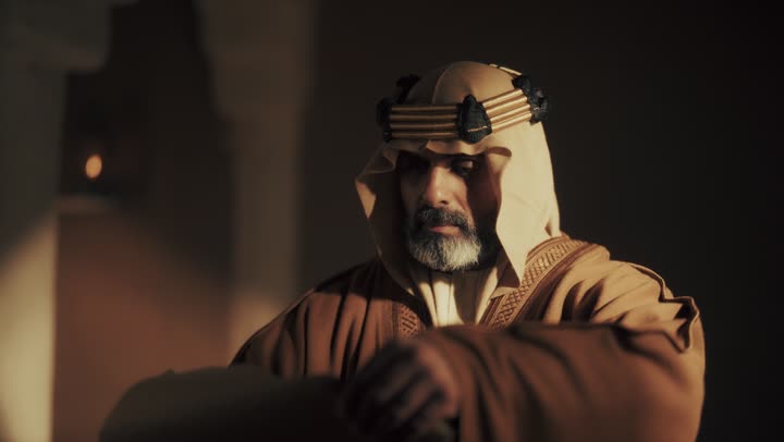 An elderly Arab Saudi Gulf man wearing a bisht and agal on Founding Day opens an old paper wrap and reads the message inside it, commemorating the establishment of the first Saudi state by Imam Muhammad bin Saud, on the day we began, February 22, 1727 AD, pride in the achievements of the nation, and the realization of national identity.