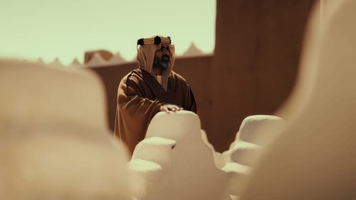 رجل كبير السن عربي سعودي خليجي يرتدي البشت وعقال يوم التأسيس يقف على مبنى طيني, ذكرى تأسيس الدوله السعوديه الاولى على يد الامام محمد بن سعود, يوم بدينا 22 فبراير 1727م, العمق التاريخي والحضاري للمملكة، مفهوم حب الوطن والانتماء اليه