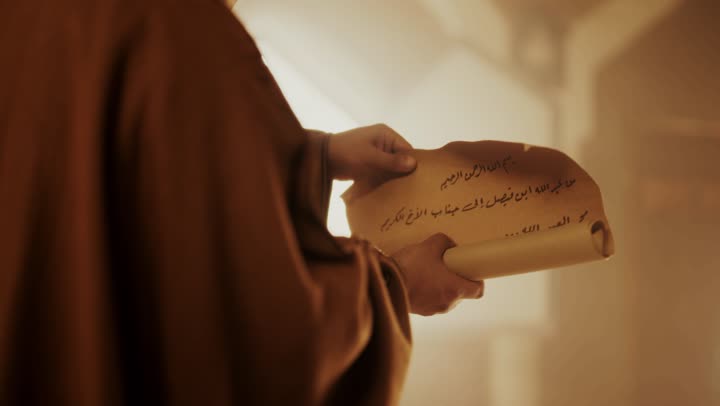 An elderly Arab Saudi Gulf man wearing a bisht and agal on Founding Day is looking at the contents of a paper scroll inside a mud building, commemorating the founding of the first Saudi state by Imam Muhammad bin Saud, on the day we began, February 22, 1727. The historical and cultural depth of the Kingdom, wearing traditional attire reflects the heritage.