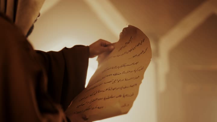 An elderly Arab Saudi Gulf man wearing a bisht and agal on Founding Day is looking at the contents of a paper scroll inside a mud building, commemorating the founding of the first Saudi state by Imam Muhammad bin Saud, on the day we began, February 22, 1727. The historical and cultural depth of the Kingdom, wearing traditional attire reflects the heritage.