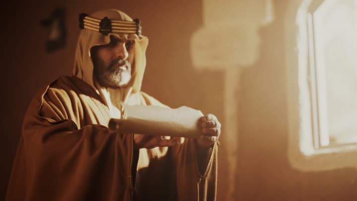 An elderly Arab Saudi Gulf man wearing a bisht and agal on the day of the foundation holds a scroll in his hand inside a clay building, commemorating the establishment of the first Saudi state by Imam Muhammad bin Saud, on the day we began, February 22, 1727 AD. The historical and cultural depth of the Kingdom, wearing traditional attire reflects the heritage.