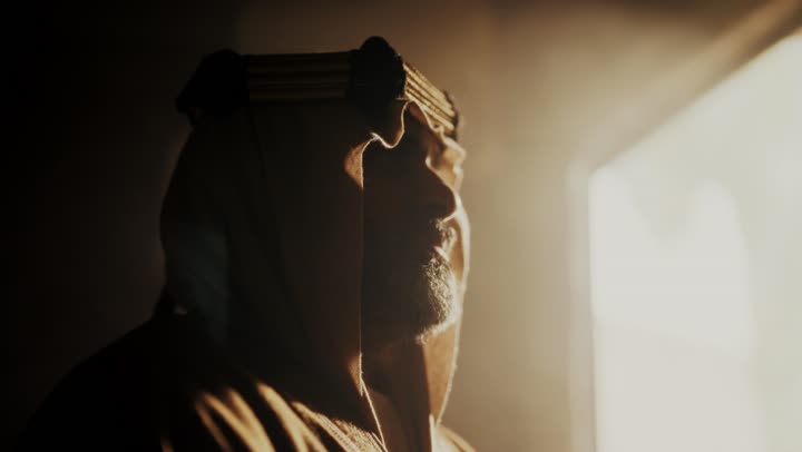 رجل كبير السن عربي سعودي خليجي يرتدي البشت وعقال يوم التأسيس يقف يجدية ووقار داخل مبنى طيني, ذكرى تأسيس الدوله السعوديه الاولى على يد الامام محمد بن سعود, يوم بدينا 22 فبراير 1727م,  العمق التاريخي والحضاري للمملكة، مفهوم حب الوطن والانتماء اليه