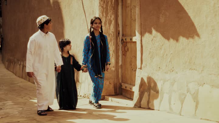 3 اخوه عربيين سعوديين خليجيين يرتدون زي شعبي تراثي يوم التأسيس يسيروا في حي طيني مع مسك الايدي, ذكرى تأسيس الدوله السعوديه الاولى على يد الامام محمد بن سعود, يوم بدينا 22 فبراير 1727م,  العمق التاريخي والحضاري للمملكة، مفهوم حب الوطن والانتماء اليه