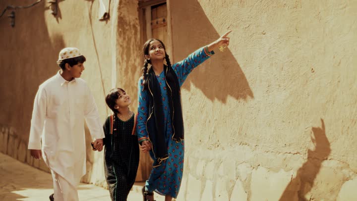 3 اخوه عربيين سعوديين خليجيين يرتدون زي شعبي تراثي يوم التأسيس يسيروا في حي طيني مع مسك الايدي, ذكرى تأسيس الدوله السعوديه الاولى على يد الامام محمد بن سعود, يوم بدينا 22 فبراير 1727م,  العمق التاريخي والحضاري للمملكة، مفهوم حب الوطن والانتماء اليه