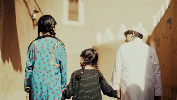 تصوير من الخلف ل 3 اخوه عربيين سعوديين خليجيين يرتدون زي شعبي تراثي يوم التأسيس يتجولوا في حي طيني مع مسك الايدي, ذكرى تأسيس الدوله السعوديه الاولى على يد الامام محمد بن سعود, يوم بدينا 22 فبراير 1727م,  العمق التاريخي والحضاري للمملكة، مفهوم حب الوطن والانتماء اليه