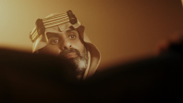 رجل كبير السن عربي سعودي خليجي يرتدي البشت وعقال يوم التأسيس يقلب صفحات كتاب تاريخي, ذكرى تأسيس الدوله السعوديه الاولى على يد الامام محمد بن سعود, يوم بدينا 22 فبراير 1727م,  العمق التاريخي والحضاري للمملكة، ارتداء الأزياء التقليدية تعكس التراث