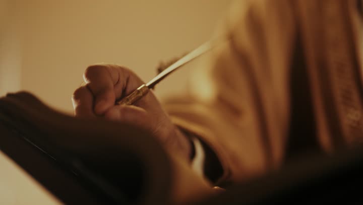 رجل كبير السن عربي سعودي خليجي يرتدي البشت وعقال يوم التأسيس يكتب رسالة على لفافة ورقية قديمة, ذكرى تأسيس الدوله السعوديه الاولى على يد الامام محمد بن سعود, يوم بدينا 22 فبراير 1727م, ارتداء الأزياء التقليدية تعكس التراث, العمق التاريخي والحضاري للمملكة